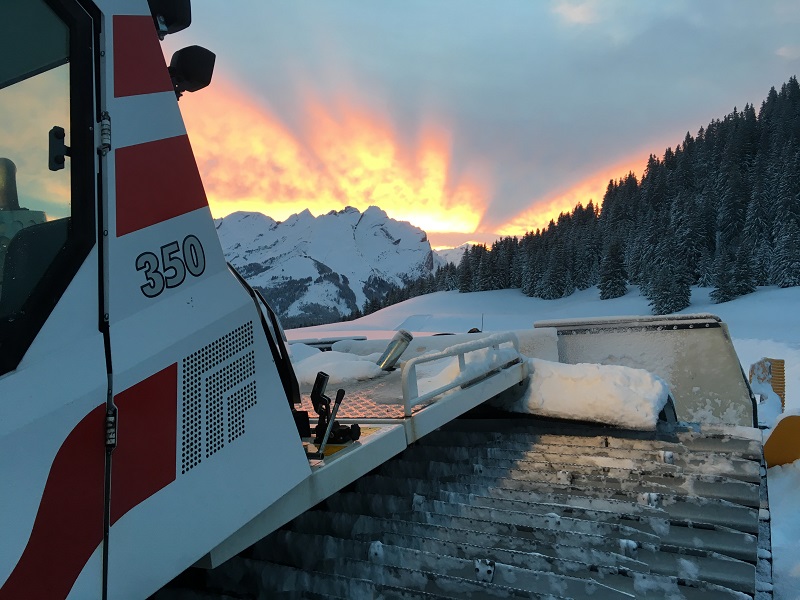 Lever de soleil sur la dameuse et les pistes de ski de fond.